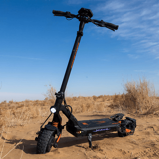 KuKirin G2 Master elscooter parkerad i sandig terräng med klar blå himmel